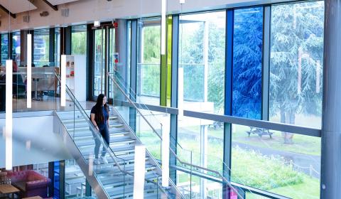 Aston student walks down steps in student union building