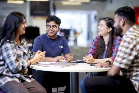 Aston students sit at a table, talking and laughing